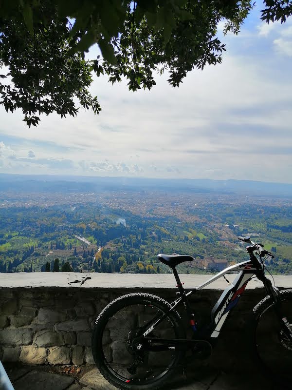 A bike next to a wall with the view of Florence from Fiesole beneath it